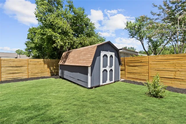 a view of a house with a big yard and potted plants and large tree