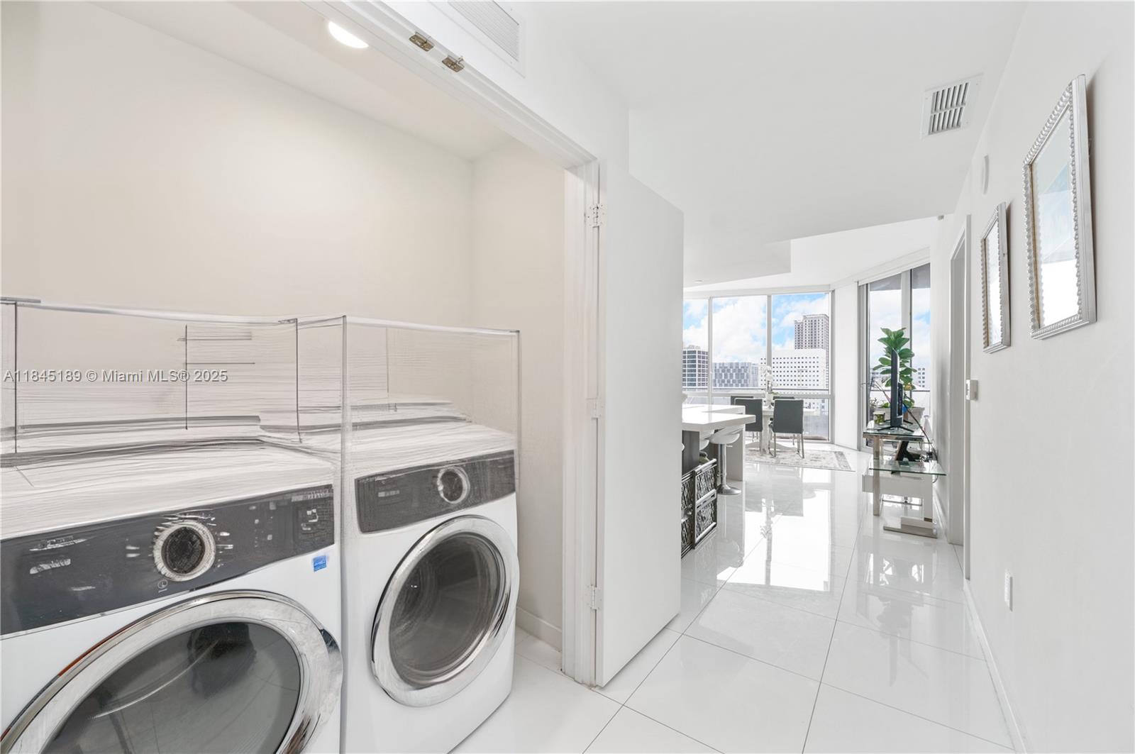 851 Northeast 1st Avenue, Unit 1410 Miami, FL 33132 - Photo 40 of 43 a view of washer and dryer with kitchen in the background