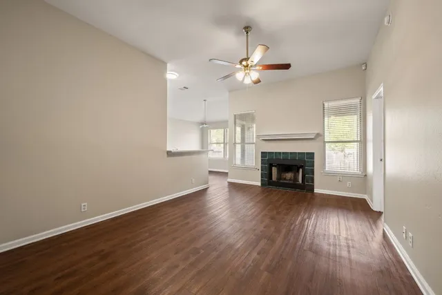 an empty room with wooden floor fireplace and windows
