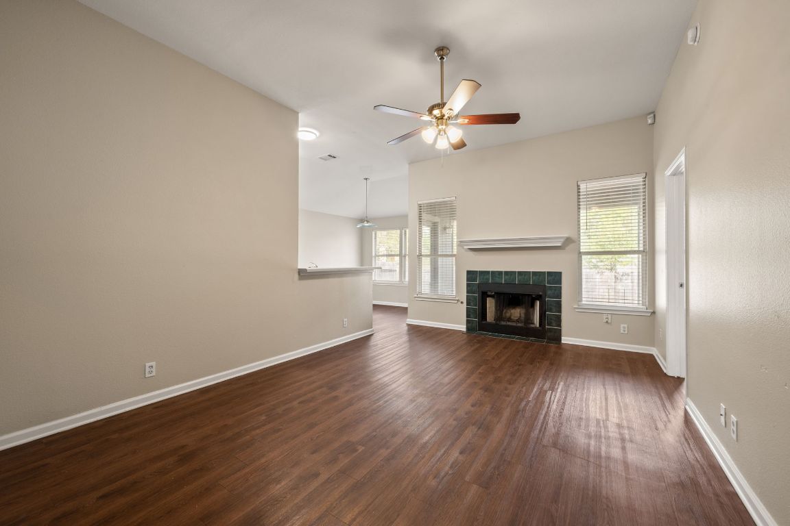 4904 Gnarled Oak Cove Austin, TX 78744 - Photo 12 of 38 an empty room with wooden floor fireplace and windows
