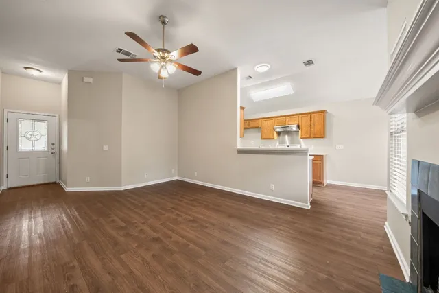 an empty room with wooden floor a ceiling fan and windows