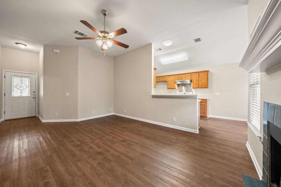 4904 Gnarled Oak Cove Austin, TX 78744 - Photo 15 of 38 an empty room with wooden floor a ceiling fan and windows