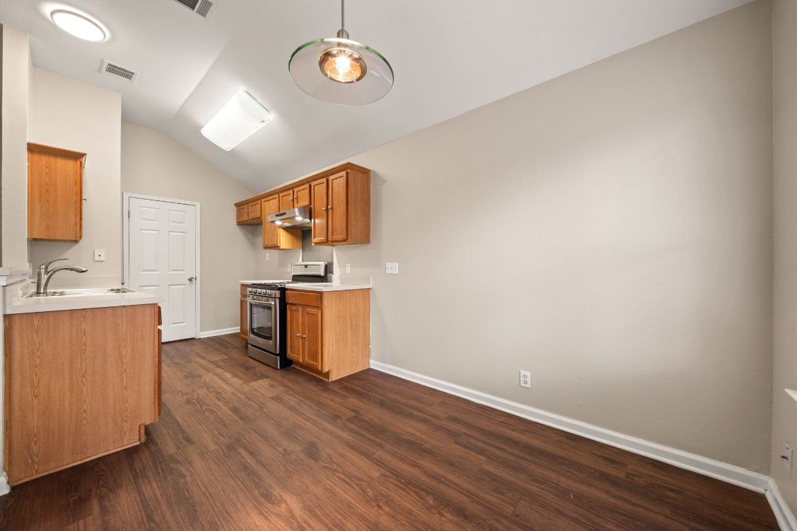 4904 Gnarled Oak Cove Austin, TX 78744 - Photo 17 of 38 a kitchen with a wooden floor and a stove top oven