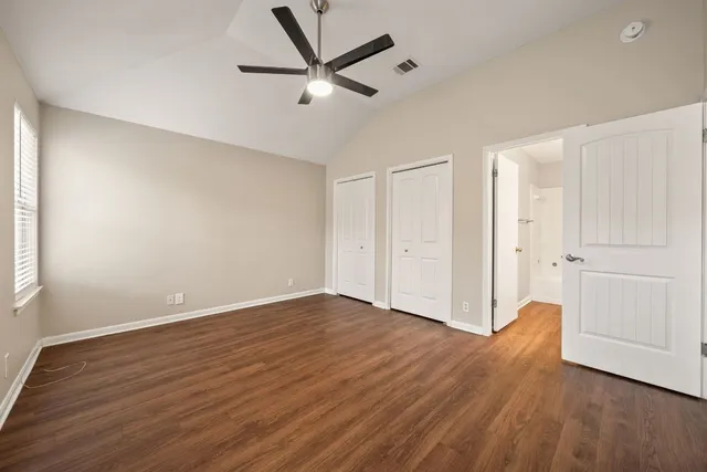 an empty room with wooden floor and windows