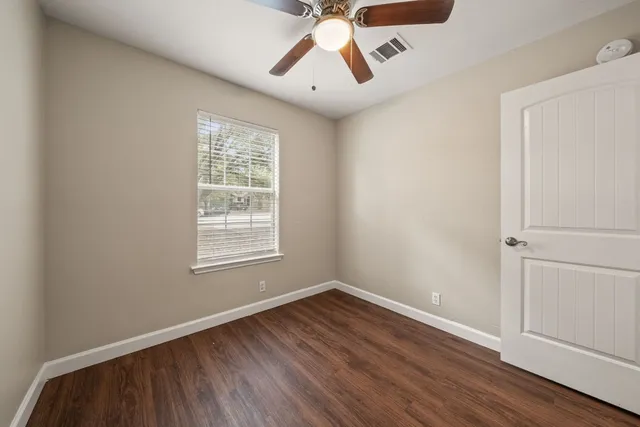 a view of an empty room with wooden floor and a window
