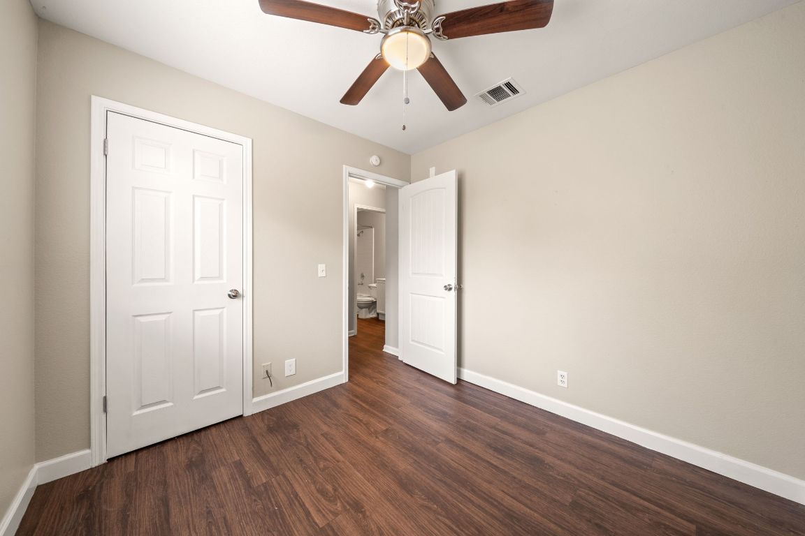 4904 Gnarled Oak Cove Austin, TX 78744 - Photo 10 of 38 an empty room with wooden floor and ceiling fan