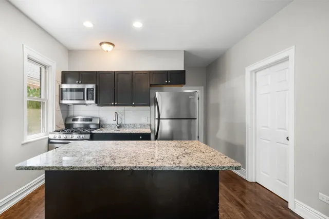 a kitchen with kitchen island a counter top space cabinets a refrigerator and a sink