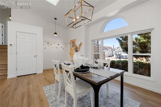 7827 Swiftrun Road Colorado Springs, CO 80920 - Photo 11 of 48 Dining space featuring light wood-type flooring, baseboards, high vaulted ceiling, and a notable chandelier