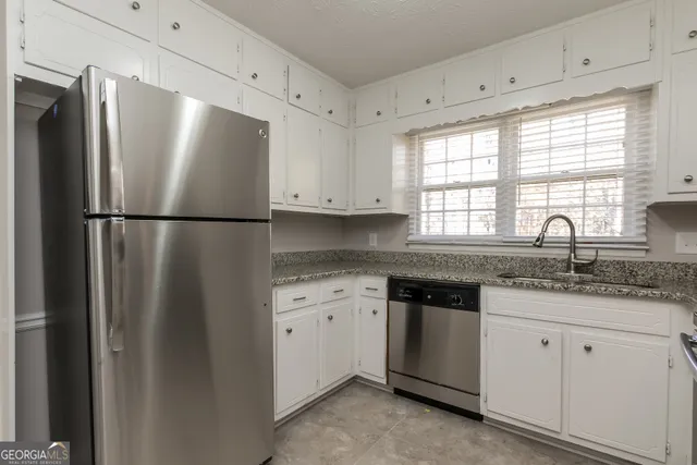 a kitchen with granite countertop white cabinets white stainless steel appliances and a sink