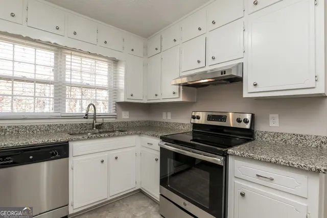 a kitchen with granite countertop white cabinets and a stove