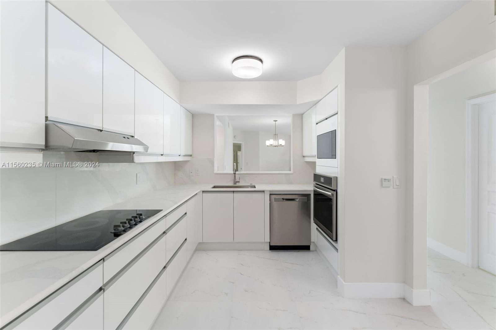 8925 Collins Avenue, Unit 2J Surfside, FL 33154 - Photo 15 of 62 a kitchen with kitchen island white cabinets and white appliances