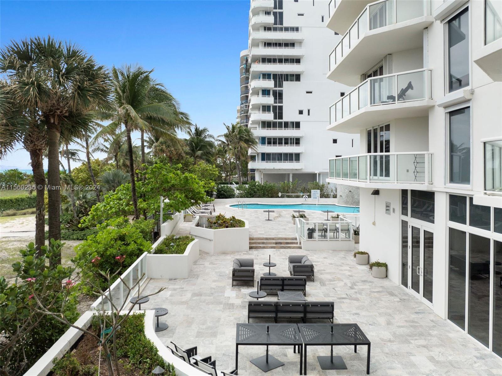 8925 Collins Avenue, Unit 2J Surfside, FL 33154 - Photo 28 of 62 a view of a patio with couches and table and chairs with wooden floor and fence and a palm tree