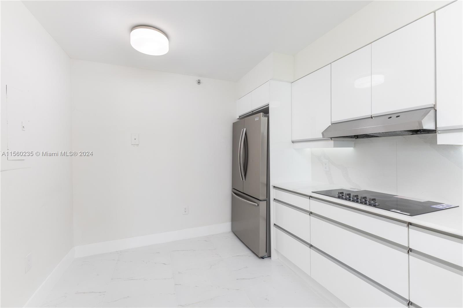 8925 Collins Avenue, Unit 2J Surfside, FL 33154 - Photo 51 of 62 a kitchen with cabinets and a refrigerator
