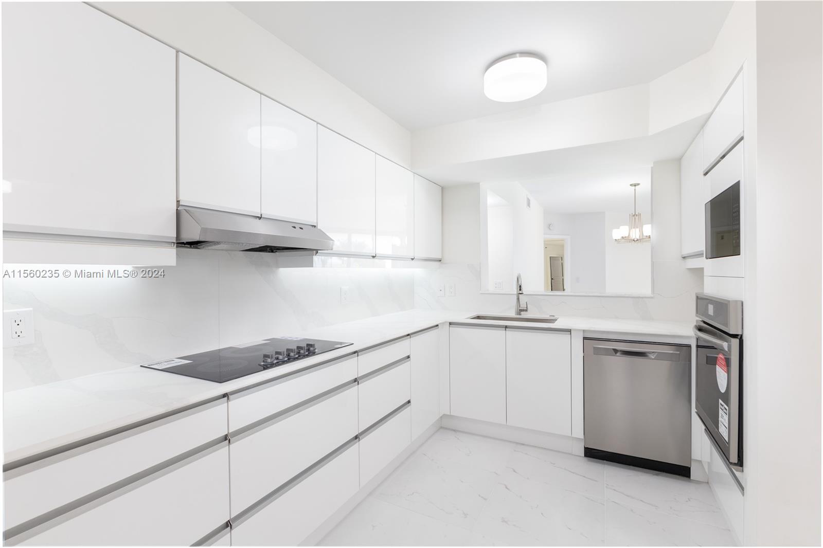 8925 Collins Avenue, Unit 2J Surfside, FL 33154 - Photo 53 of 62 a kitchen with stainless steel appliances granite countertop a sink and cabinets with wooden floor