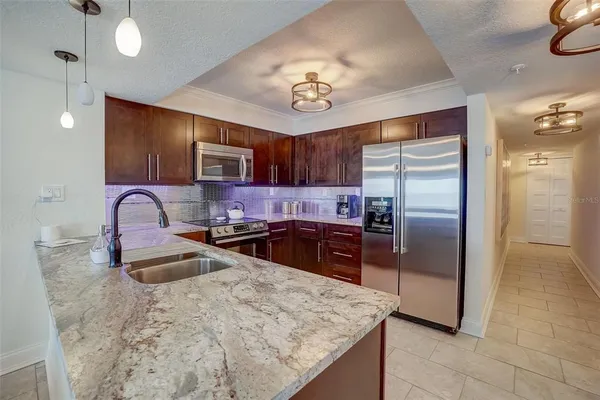 a kitchen with stainless steel appliances granite countertop a refrigerator a sink a stove a microwave and island