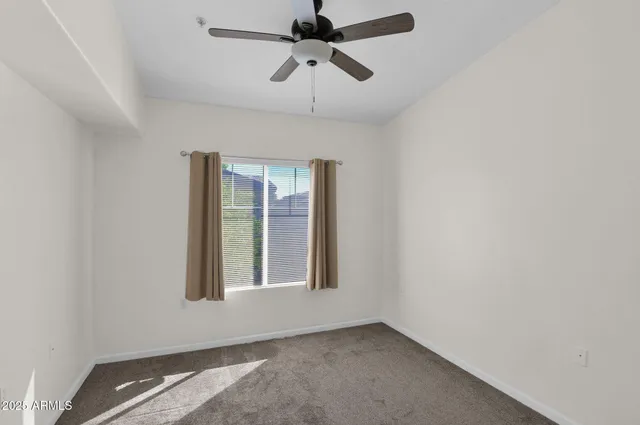 an empty room with windows and fan