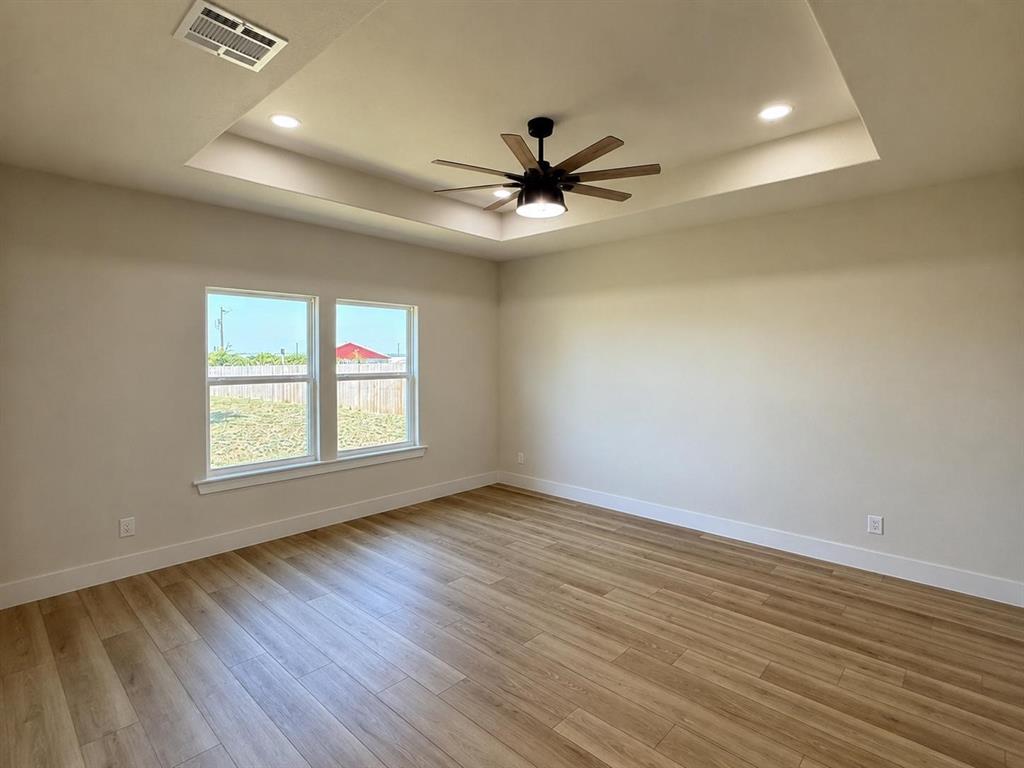 413 North Cleburne Whitney Road Rio Vista, TX 76093 - Photo 7 of 20 Spacious primary suite with an elegant tray ceiling with recessed lighting, a modern ceiling fan with integrated lighting, and two large windows