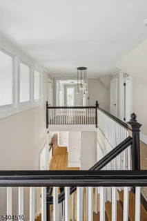 a view of a hallway to a livingroom with wooden floor and stairs