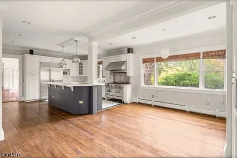 a kitchen with stainless steel appliances granite countertop a stove a sink dishwasher and a large refrigerator with wooden floor