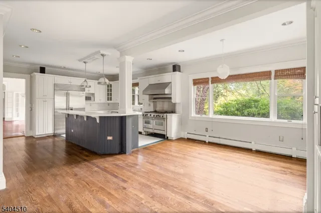 a kitchen with stainless steel appliances granite countertop a stove a sink dishwasher and a large refrigerator with wooden floor