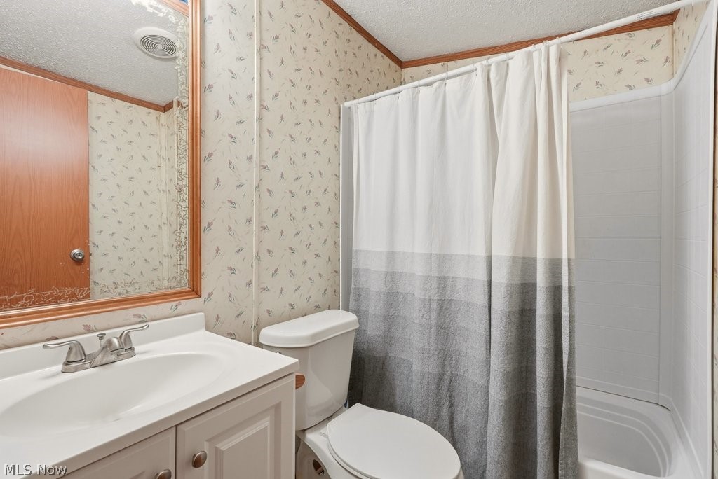 6507 Robby Lane Ravenna, OH 44266 - Photo 20 of 25 Bathroom with a textured ceiling, wallpapered walls, vanity, ornamental molding, and shower / bathtub combination with curtain