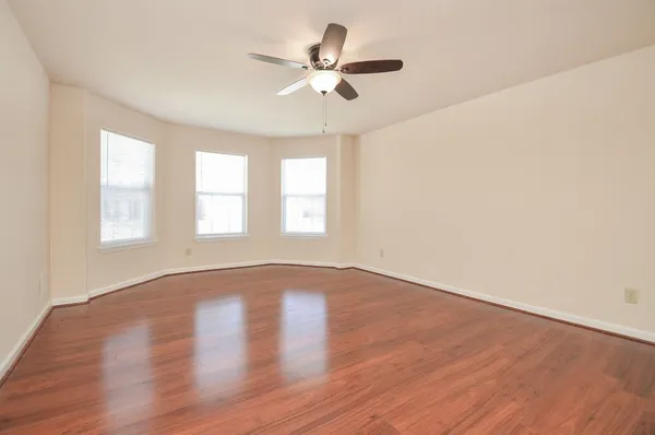 a view of an empty room with a window and wooden floor