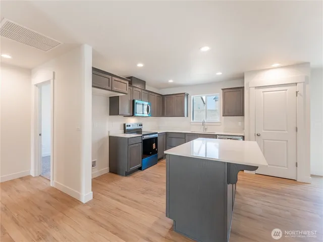 a large kitchen with stainless steel appliances kitchen island a large counter top and a wooden floors
