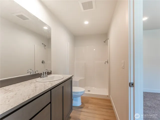 a bathroom with a granite countertop sink a toilet and shower