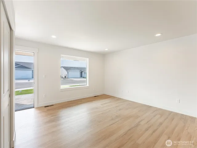 an empty room with wooden floor and windows