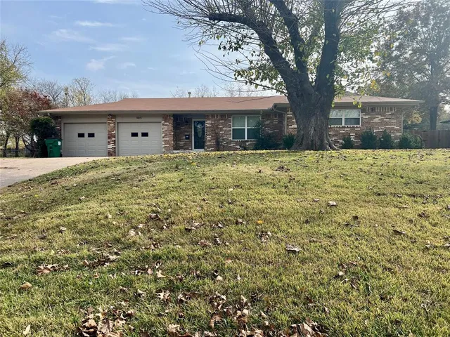 a large tree in front of a white house