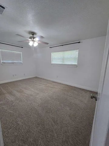 an empty room with a chandelier fan and windows