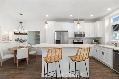 a kitchen with stainless steel appliances kitchen island granite countertop a dining table chairs and white cabinets