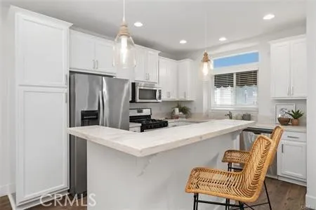 a kitchen with stainless steel appliances a refrigerator a sink a stove a table and chairs