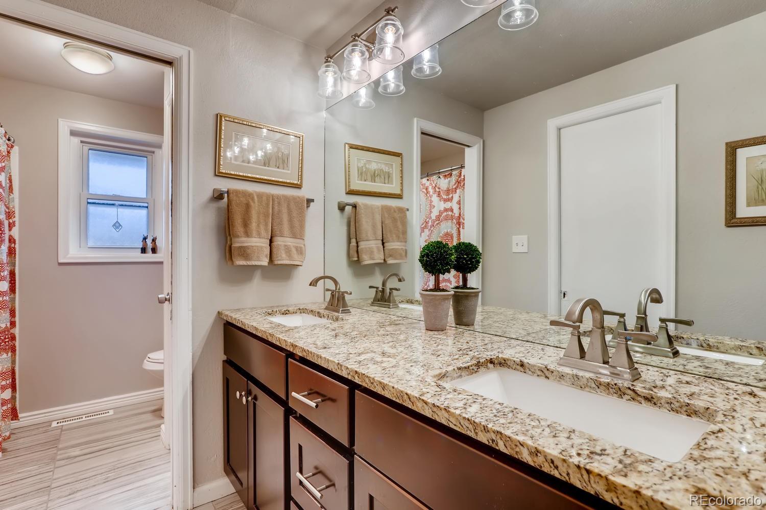 1502 Juniper Street Longmont, CO 80501 - Photo 18 of 28 a bathroom with a granite countertop double vanity sink and a mirror
