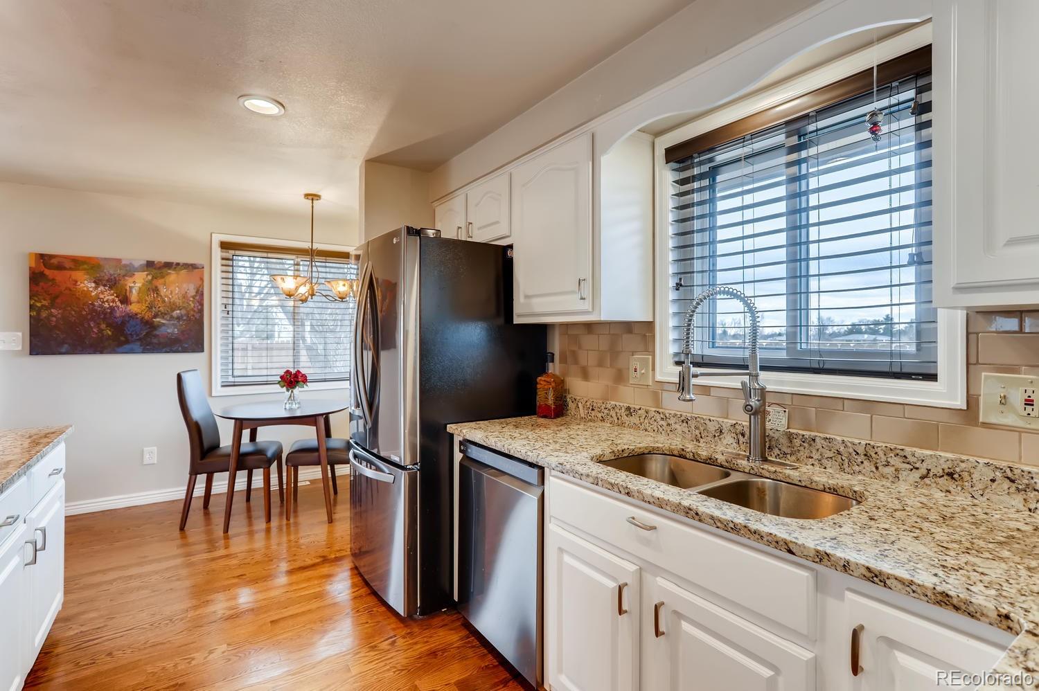 1502 Juniper Street Longmont, CO 80501 - Photo 8 of 28 a kitchen with stainless steel appliances granite countertop a refrigerator a sink a stove and a dining table with wooden floor