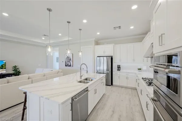 a large kitchen with a large counter top a sink a stove a refrigerator and a center island