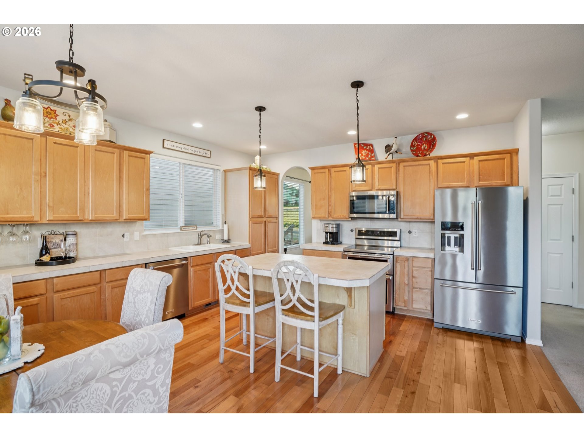 2404 Southeast Jasmine Way Gresham, OR 97080 - Photo 11 of 48 a kitchen with stainless steel appliances kitchen island granite countertop a refrigerator a stove top oven a sink dishwasher and white cabinets with wooden floor