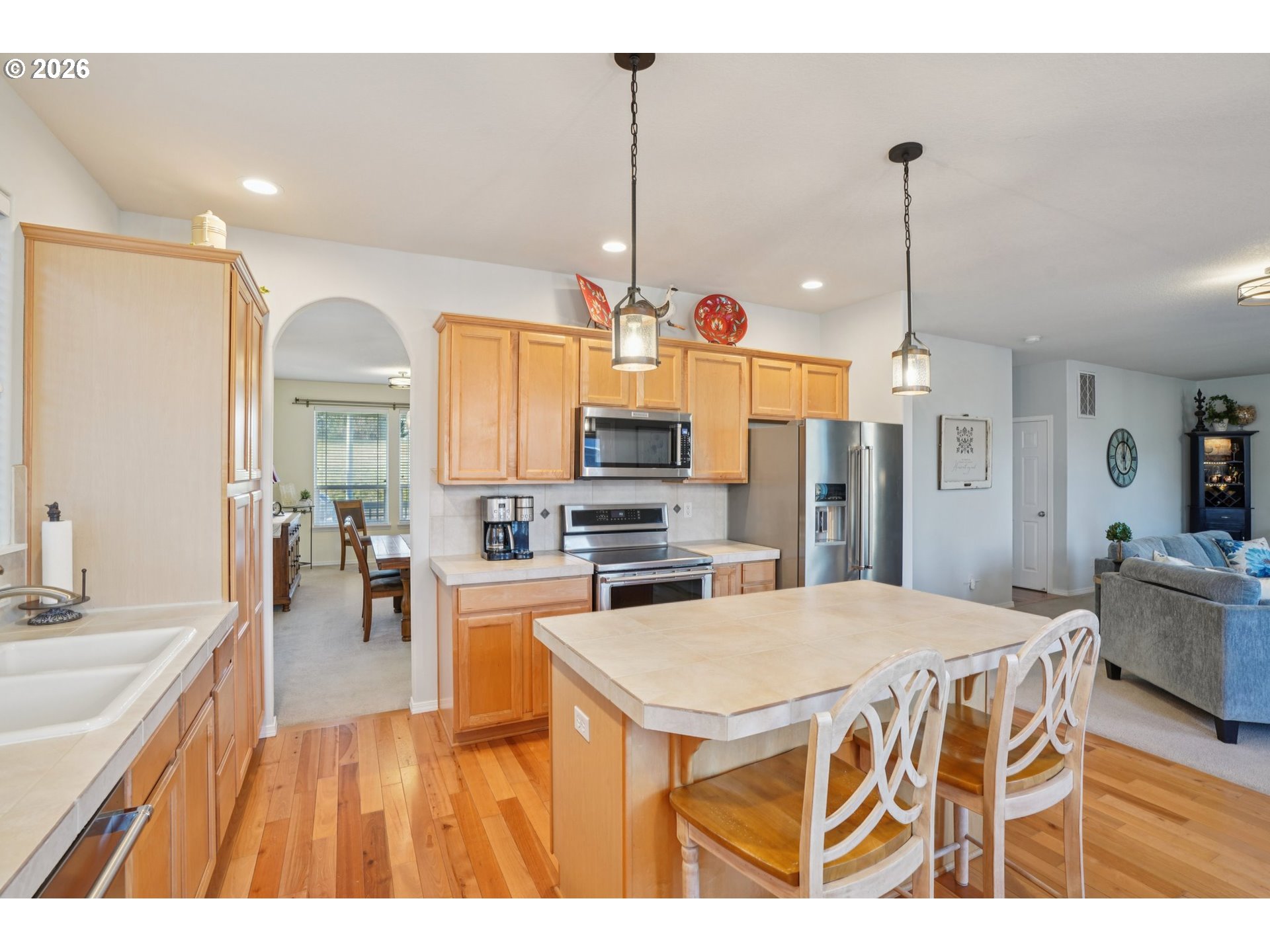 2404 Southeast Jasmine Way Gresham, OR 97080 - Photo 10 of 48 a open kitchen with stainless steel appliances kitchen island granite countertop a refrigerator a stove a sink a dining table and chairs with wooden floor