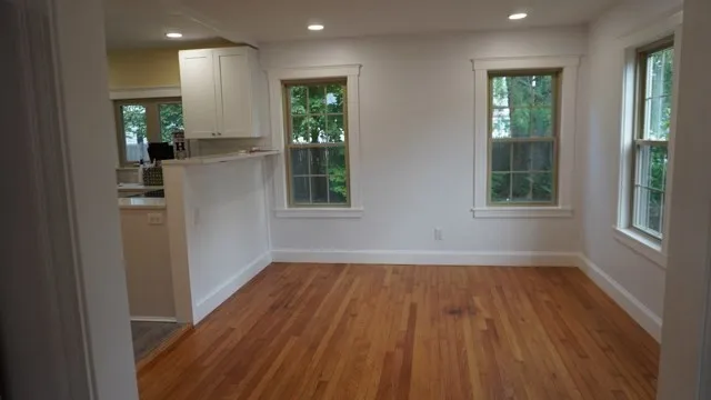 a view of an empty room with wooden floor and a window