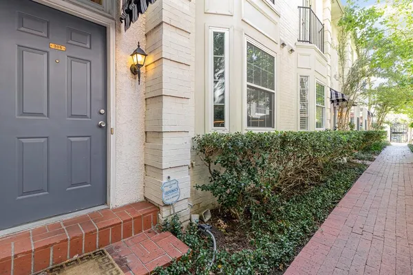 a view of a brick house with plants and wooden walls