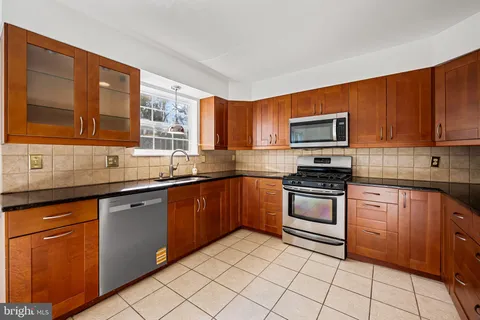 a kitchen with stainless steel appliances granite countertop wooden cabinets a stove top oven a sink and dishwasher