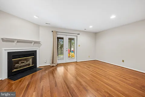 a view of an empty room with wooden floor fireplace and a window