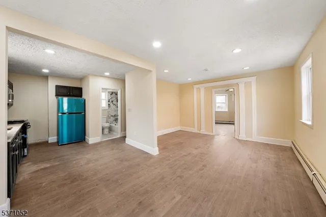 a view of an empty room with wooden floor and windows