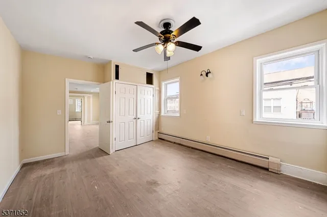 an empty room with ceiling fan and windows