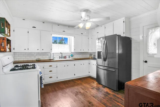 a kitchen with granite countertop a refrigerator cabinets and wooden floor