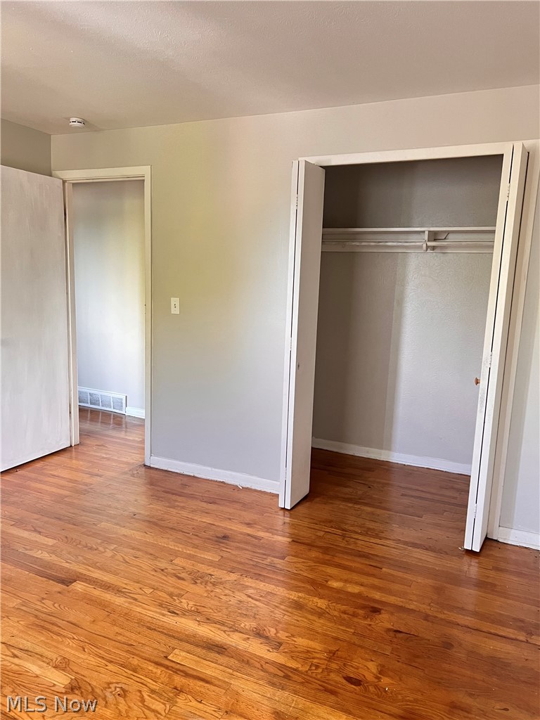 16350 Rockside Road Maple Heights, OH 44137 - Photo 23 of 34 Hardwood flooring throughout featuring painted walls, white trim, and a built-in closet with bi-fold doors