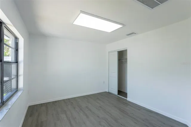 an empty room with wooden floor and windows
