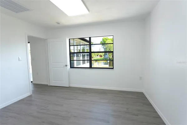 an empty room with wooden floor and windows
