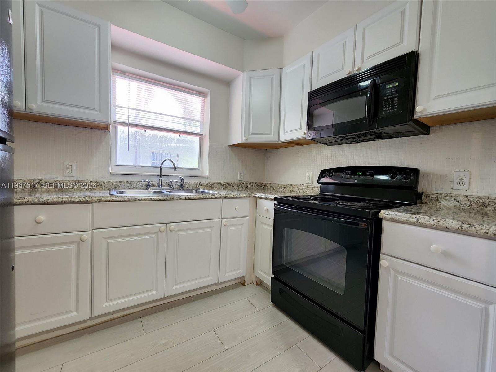 8335 Northeast 3rd Avenue, Unit 1 Miami, FL 33138 - Photo 6 of 12 a kitchen with stainless steel appliances granite countertop white cabinets granite counter tops and a window