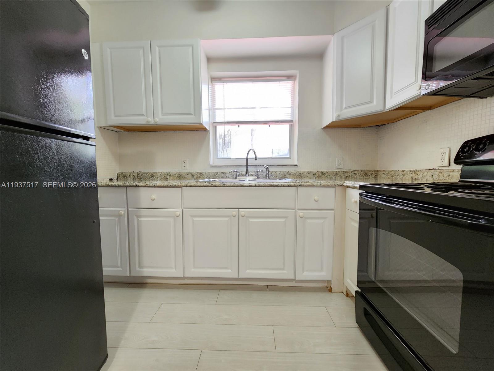 8335 Northeast 3rd Avenue, Unit 1 Miami, FL 33138 - Photo 7 of 12 a kitchen with granite countertop white cabinets stainless steel appliances and a sink